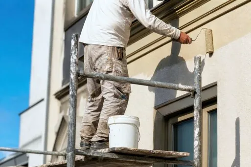 Painter on scaffolding rolling a stucco exterior in Palos Verdes